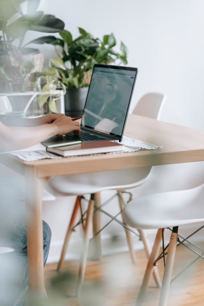 Unrecognizable worker typing on laptop at table with flowers